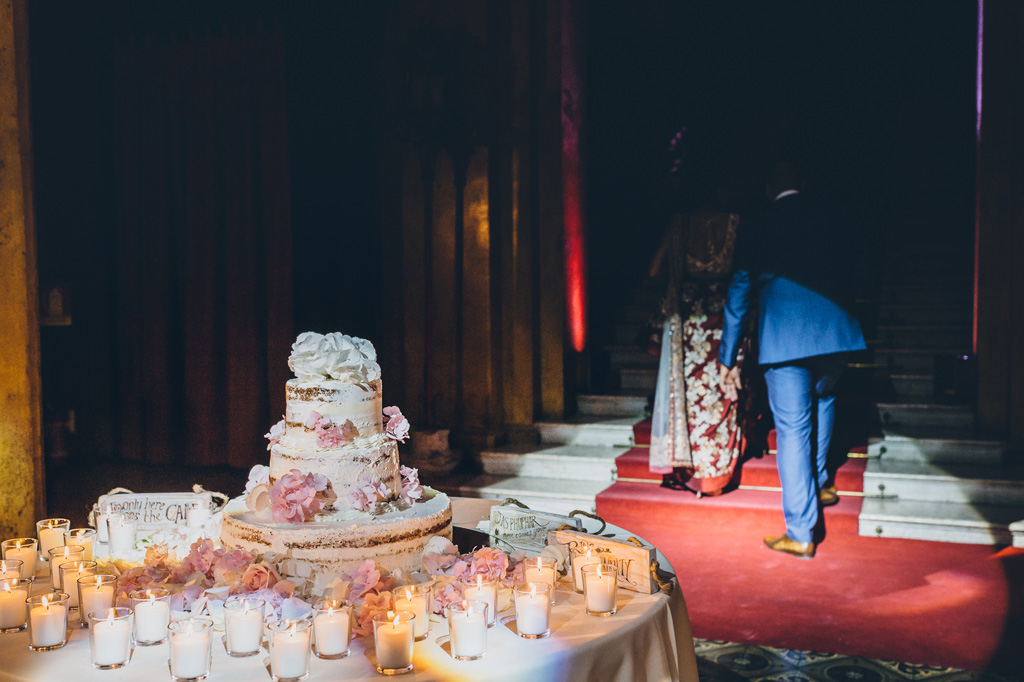 Fotografo Matrimonio Villa Erba Gli sposi superano la torta dalla penombra della sala