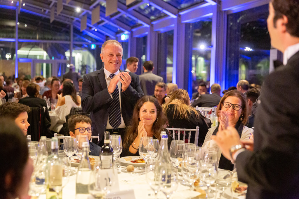 Fotografo Cena Aziendale Milano EUGA Villa Necchi Campiglio Gli invitati applaudono divertiti il prestigiatore durante la cena di gala presso Villa Necchi Campigiglio